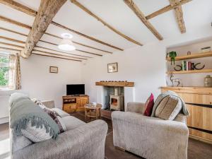 a living room with two chairs and a fireplace at Wrens Beck Cottage in Ousby