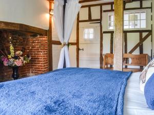 um quarto com uma cama azul e uma parede de tijolos em The Cottage At Harple Farm em Detling