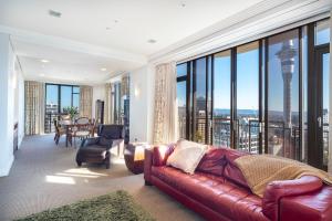 een woonkamer met een bank en grote ramen bij Luxury Penthouse Apartment in Auckland