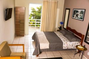 1 dormitorio con 1 cama y puerta a un balcón en Residencial Mar Azul Praia da Pinheira, en Palhoça