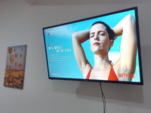 uma televisão de ecrã plano com um poster de uma mulher em W's Hostel em San José