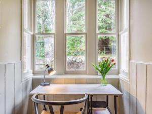 een tafel met een vaas met bloemen in een raam bij East Lodge in Contin