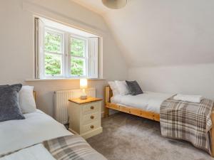 een slaapkamer met 2 bedden en een lamp op een nachtkastje bij East Lodge in Contin