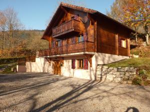 a wooden house with a balcony on a road at Chalet confortable avec 4 chambres, cheminée, grand terrain, proche pistes et lac - FR-1-589-107 in Le Ménil