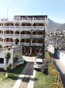 un gran edificio con coches estacionados frente a él en Hotel Tinamit, en San Pedro La Laguna