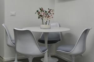 a white table with chairs and a vase with flowers at Dadà Suites in Catania