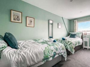 two beds in a room with green walls at Holly Cottage in Culbokie