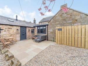 a stone cottage with a patio in front of it at Cherrytree Cottage in Chatton