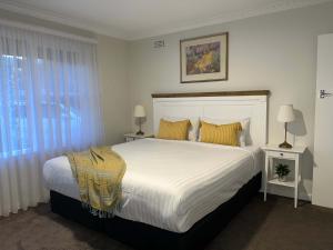 a bedroom with a large white bed with yellow pillows at Hamilton's Queanbeyan Motel in Queanbeyan