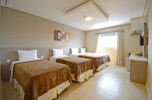 a hotel room with two beds and a window at Business Park Hotel in Hortolândia