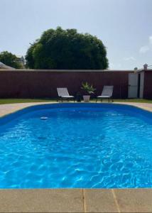 a large blue swimming pool with two chairs in a yard at Appartement cosy & calme en Rez de villa in Saint-François
