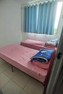 two twin beds in a room with a window at Ike village in Kota Samarahan