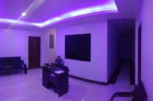 a living room with purple lighting and a tv on a wall at Junie Pension House in Moalboal