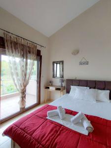 una camera da letto con un grande letto con lenzuola rosse e una finestra di Villa Artemis Keramoti a Keramotí