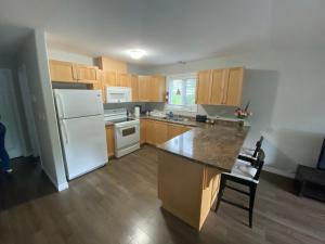 a kitchen with a white refrigerator and wooden cabinets at Nice Rooms Stay - Unit 2 in Kingston