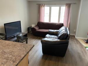 a living room with a leather couch and a television at Nice Rooms Stay - Unit 2 in Kingston