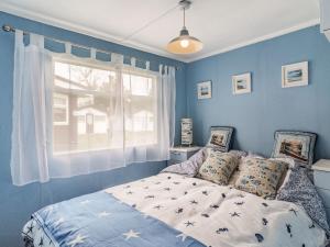 曼德斯里的住宿－Bluebird Chalet，一间卧室配有一张蓝色墙壁的床和一扇窗户