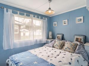 a bedroom with a bed with blue walls and a window at Bluebird Chalet in Mundesley