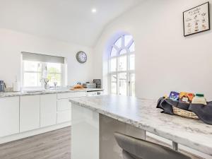 a white kitchen with a large marble counter top at Capel Y Ffynnon in Llandudno Junction