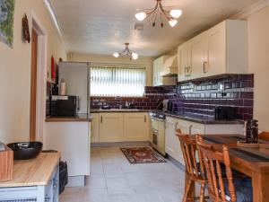 a kitchen with white cabinets and a table with chairs at Zebra House in Blaenavon
