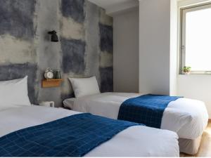a bedroom with two beds with blue and white sheets at HOTEL WAN OSAKA EBISU in Osaka