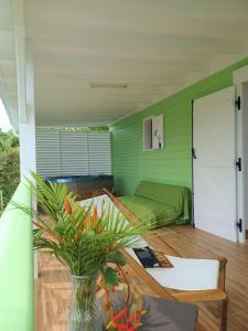 a green room with a bed and a vase with a plant at Villa Kabrit Bwa Sainte-Luce in Sainte-Luce