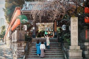 OMO3 Tokyo Akasaka by Hoshino Resort في طوكيو: ثلاثة أشخاص يصعدون سلالم معبد
