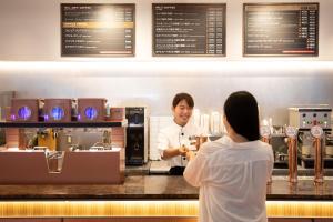 a man standing behind a counter with a woman at OMO3 Tokyo Akasaka by Hoshino Resort in Tokyo