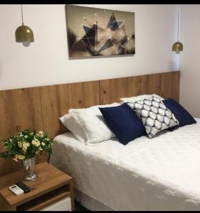 Una cama con almohadas azules y blancas y una mesa. en Guarajuba apartamento máximo 4 pessoas- 2 suítes- 170m praia en Guarajuba