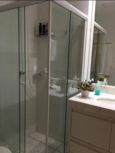 a bathroom with a glass shower and a sink at Guarajuba apartamento máximo 4 pessoas- 2 suítes- 170m praia in Guarajuba