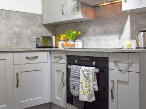 a kitchen with white cabinets and a black dishwasher at Pen Y Bont in Rhuddlan