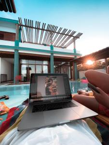 a person sitting in a swimming pool with a laptop at MelBliss Gostoso in São Miguel do Gostoso
