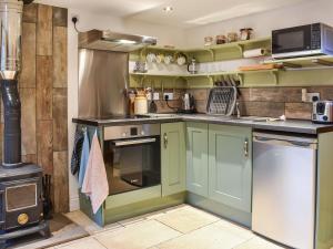 a kitchen with green cabinets and a stove at The Hayloft in Crosby Garrett