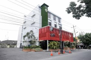 um edifício com uma fachada verde e vermelha com cones à frente em King's Palace Mitra RedDoorz em Medan