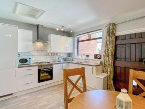 a kitchen with white cabinets and a wooden table at Wilne Cottage in Shardlow