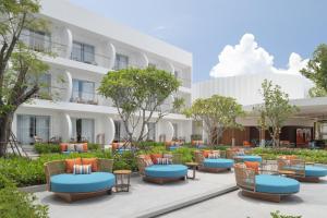 an exterior view of a hotel with tables and chairs at Avani Chaweng Samui Hotel & Beach Club - Adults Only in Chaweng
