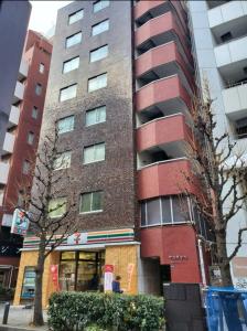 a tall red building in front of a building at 歌舞伎町ヤスオroom in Tokyo