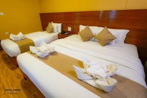 two beds in a hotel room with towels at Hotel Chino Pokhara in Pokhara