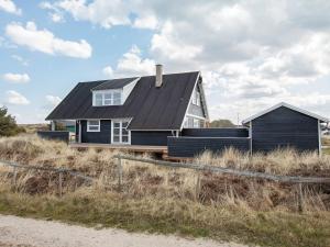 une maison avec un toit noir assise au-dessus d'un champ dans l'établissement 8 person holiday home in Thisted, à Thisted