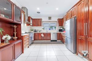 a kitchen with wooden cabinets and a stainless steel refrigerator at KozyGuru / Rockdale / Spacious Modern 2 Bedrooms Holiday Home NRO147 in Sydney