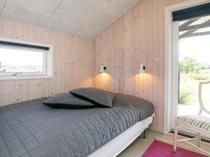 ein Schlafzimmer mit einem Bett in einem Zimmer mit Holzwänden in der Unterkunft Holiday home Blokhus XLII in Blokhus
