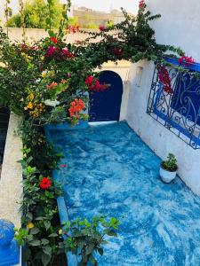 einen Garten mit Blumen und einem blauen Pool mit Wasser in der Unterkunft Chez Amel Guoumi in Oualidia