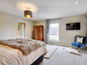 1 dormitorio con 1 cama grande y 1 silla azul en Woodhouse Lodge, en Pooley Bridge