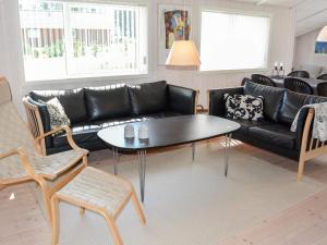 ein Wohnzimmer mit einem schwarzen Sofa und einem Tisch in der Unterkunft 6 person holiday home in L kken in Løkken