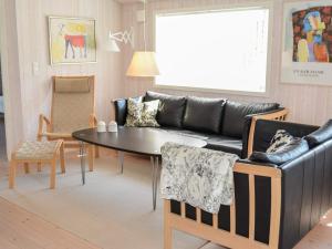 ein Wohnzimmer mit einem Sofa, einem Tisch und Stühlen in der Unterkunft 6 person holiday home in L kken in Løkken