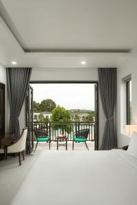 a bedroom with a bed and a balcony with chairs at DAD Resort Phú Quốc in Phú Quốc