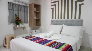 um quarto com uma cama branca e um cobertor listrado em Hotel Playa Divina em Coveñas