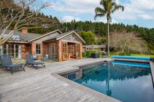 a home with a swimming pool and a house at Peace-Realm Retreat in Matakana