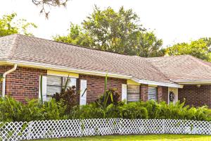 ein Backsteinhaus mit einem weißen Zaun davor in der Unterkunft Welcome to the Cottage: A Home Away from Home in Port Saint Lucie