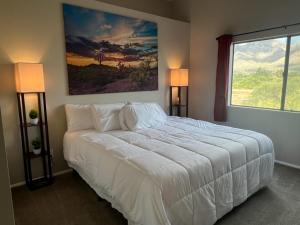 a bedroom with a white bed with a large window at The Desert Oasis at #LambertPark Tucson - 4BD + Unobstructed Mountain Views in Tucson